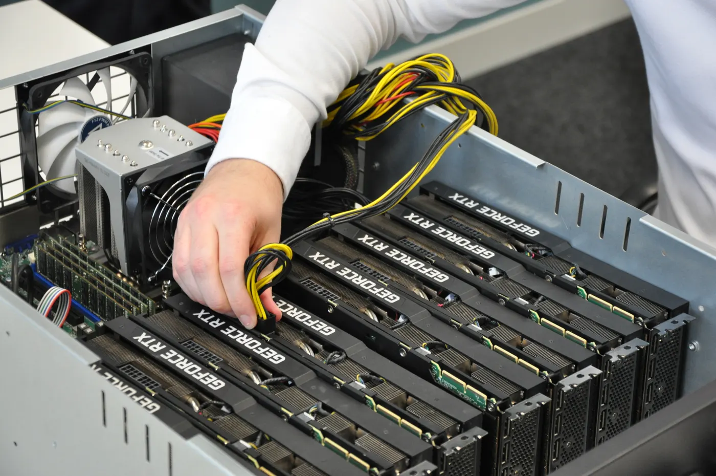 An Ollsoft engineer connecting a power cable in an open server packed with GeForce RTX graphics cards