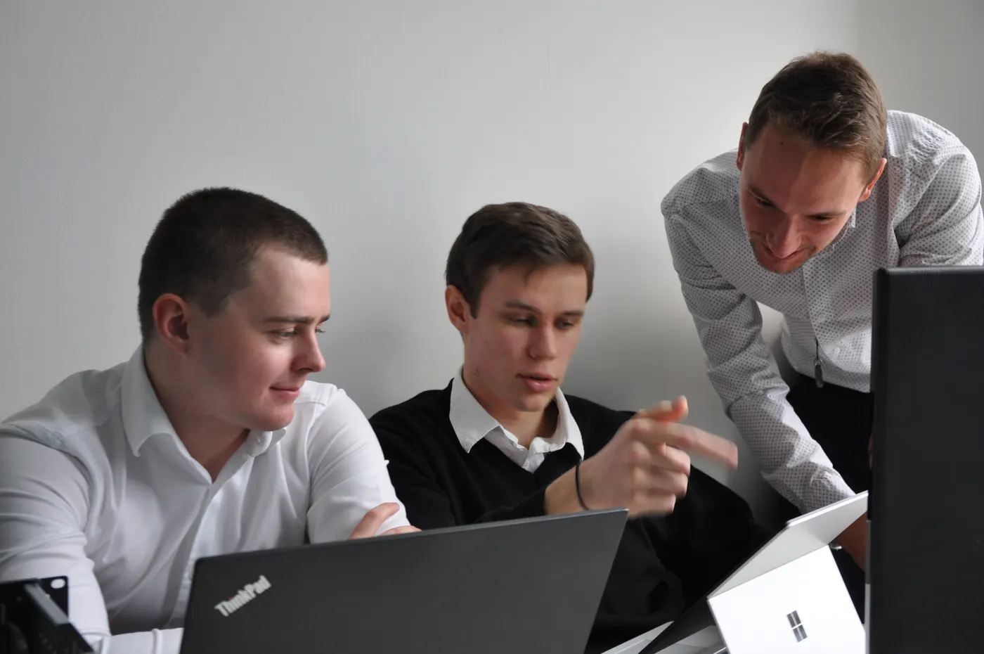Tři inženýři Ollsoftu u notebooku, jeden ukazuje na obrazovku